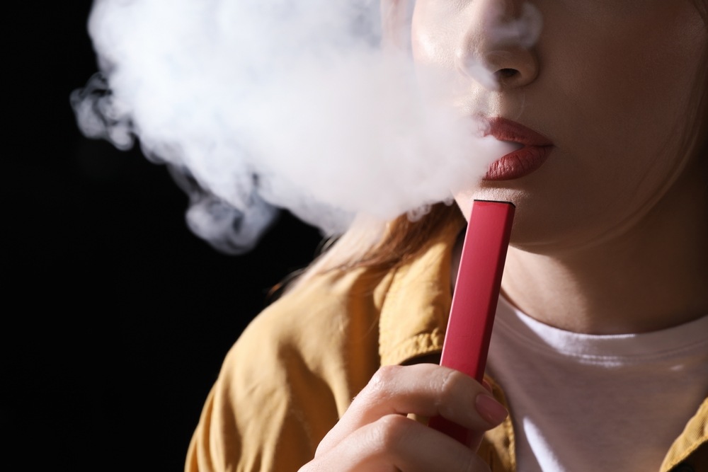 A person breathes out a thick cloud of vapor from a disposable vape.