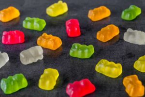 Gummy bears sit on a black table. 