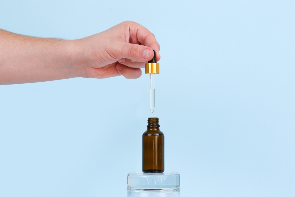 A person lifts a dropper cap from a bottle of tincture.