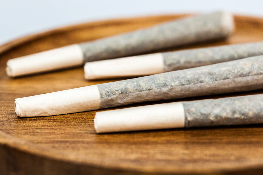 Four pre-rolls sit in a shallow wooden bowl.
