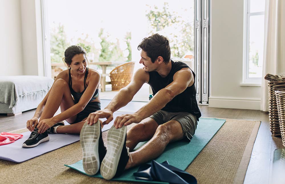 A couple exercises together on yoga mats.