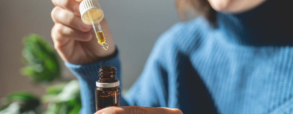 A person draws a dropper full of CBD tincture out of its bottle.