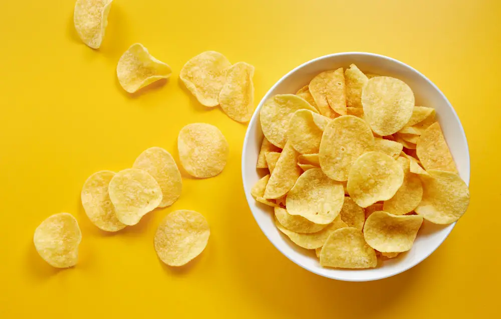 Potato chips seen from above, sitting on a yellow table.