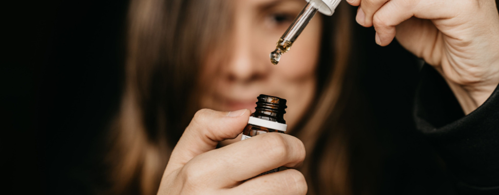 A woman removes a bottle of CBD oil from its dropper.