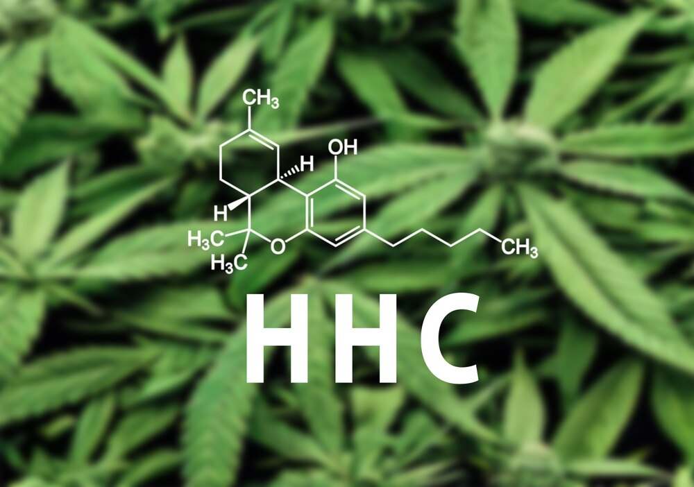 The chemical formula for HHC is shown in front of a background of hemp leaves in soft focus.