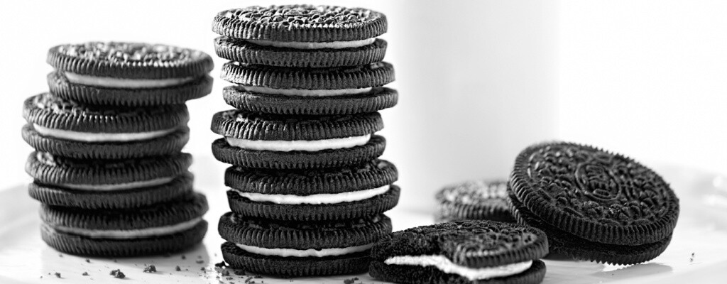 A plate of cookies sits in front of a glass of milk and a white background.