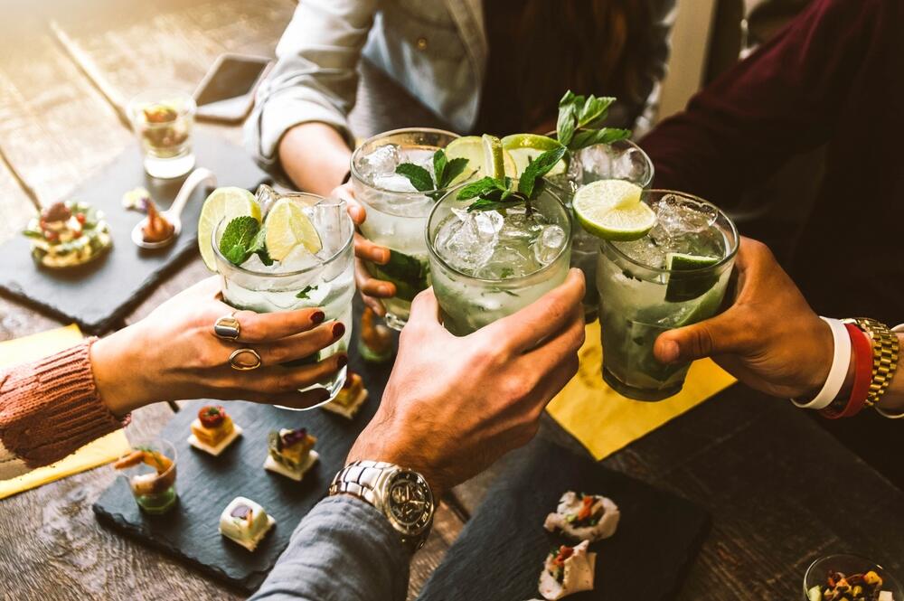 Friends toast each other with mojito-style drinks