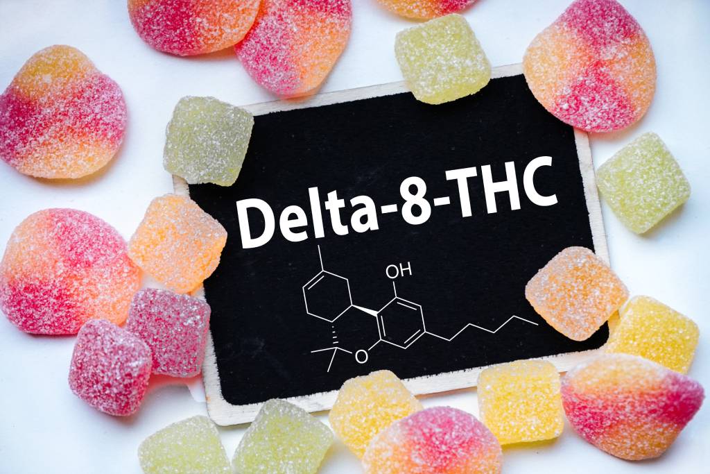 Gummies surround a chalkboard sign reading “Delta 8.”