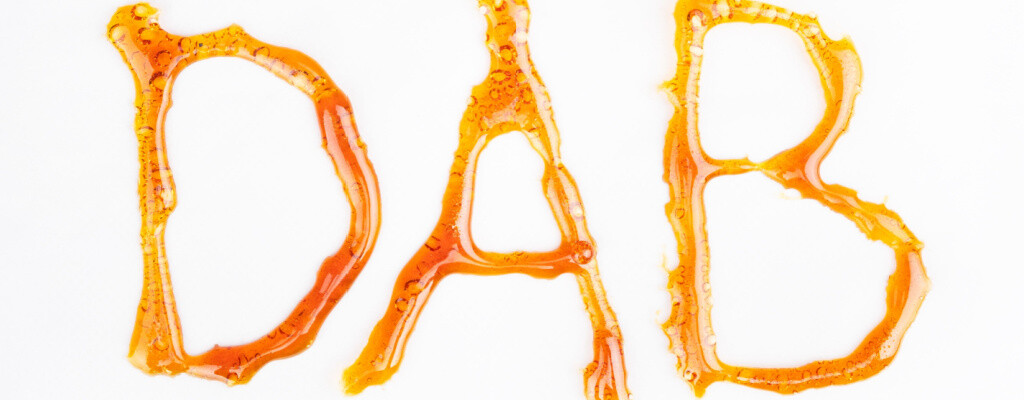 The word “Dab” spelled in capital letters using cannabinoid wax on a white background.