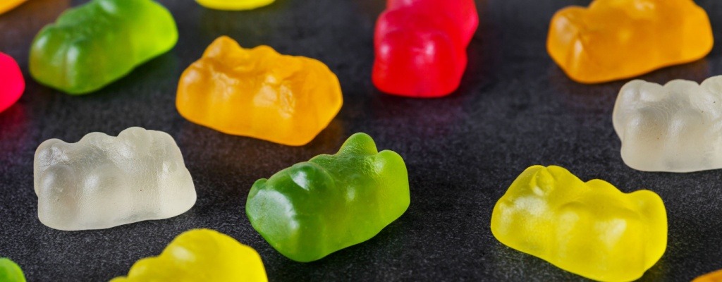 Gummy bears sit on a black table. 