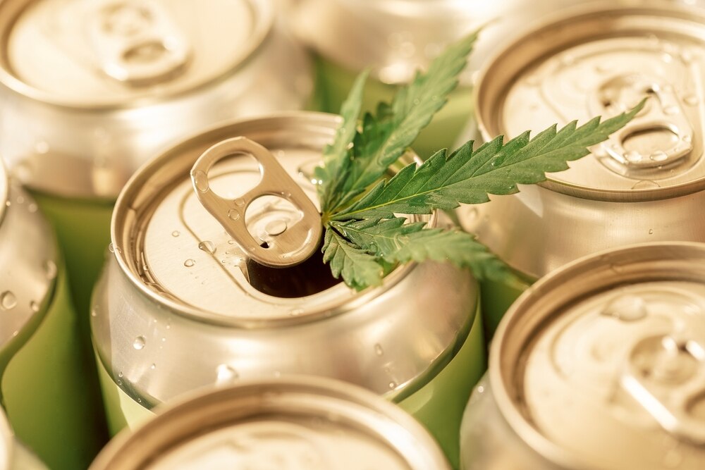 A hemp leaf sits on top of a canned beverage. 