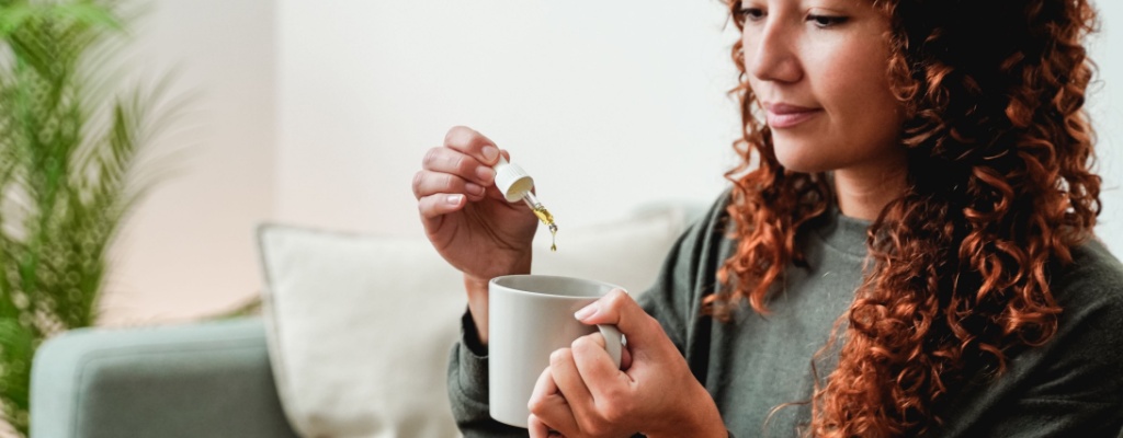 A woman adds cannabinoid oil to a beverage.