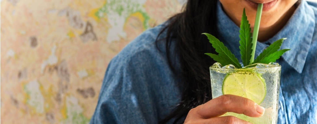 A woman drinks a THC soda from a glass.