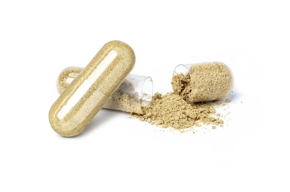 two kratom capsules one open sit against a white background