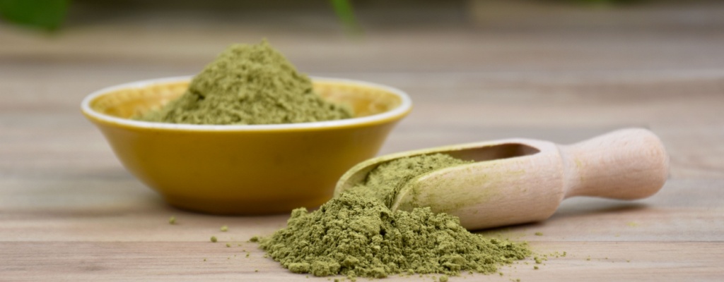 kratom powder sits in a bowl and scoop on a table