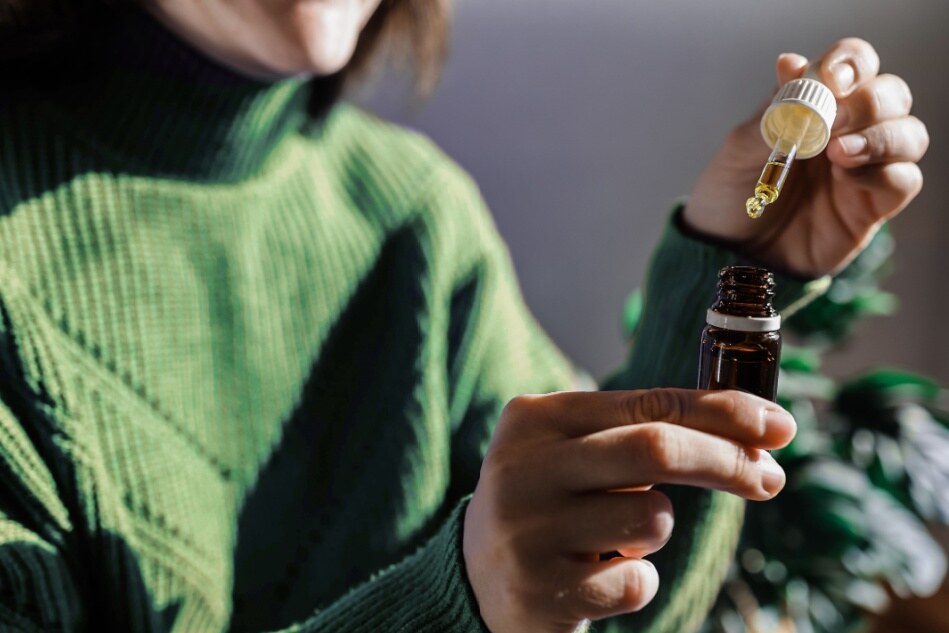 A woman holds a bottle of cannabinoid oil.