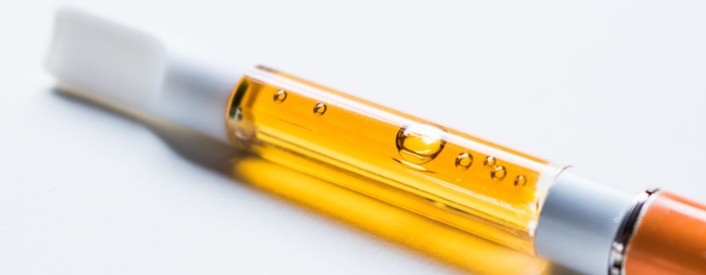 a vape pen and cartridge sit against a white background