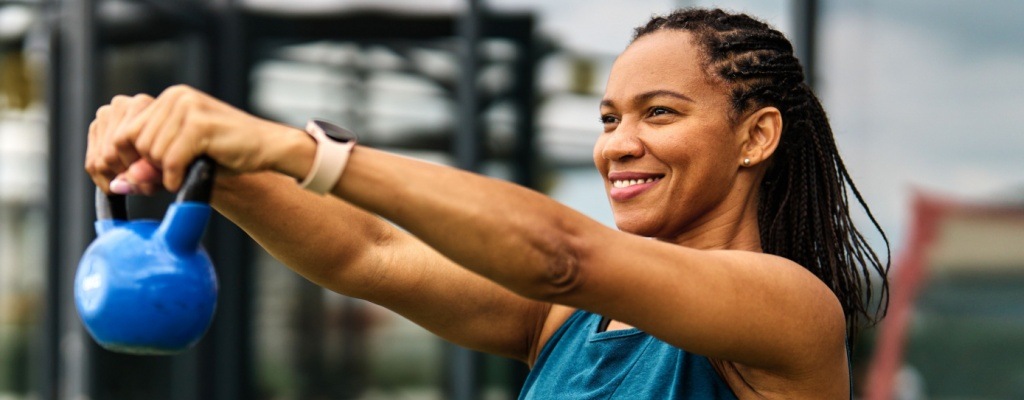 A woman lifts a kettlebell as part of a strength training workout.