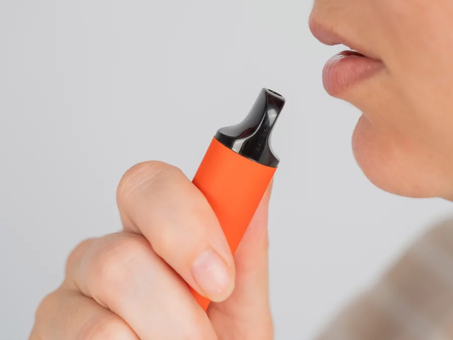 A close-up view of a woman using a disposable vape.