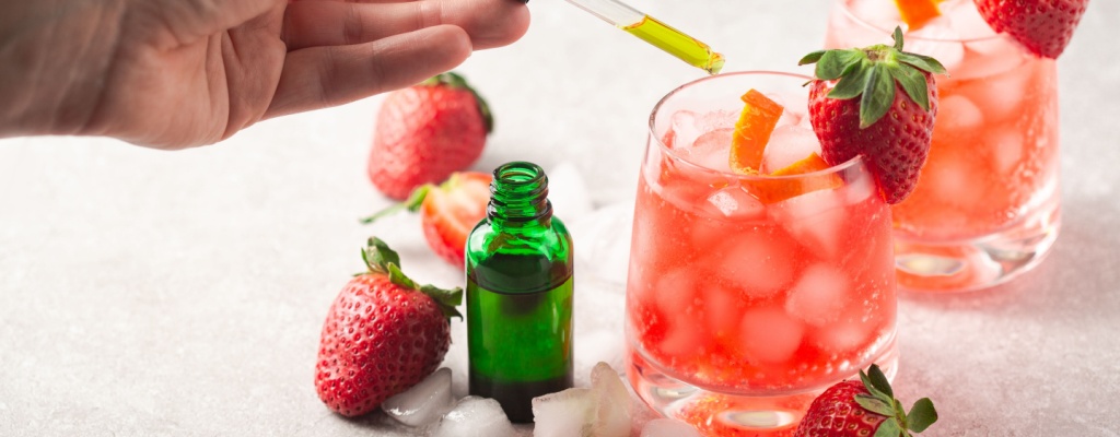 A person adds cannabinoid oil to a pair of cocktails.