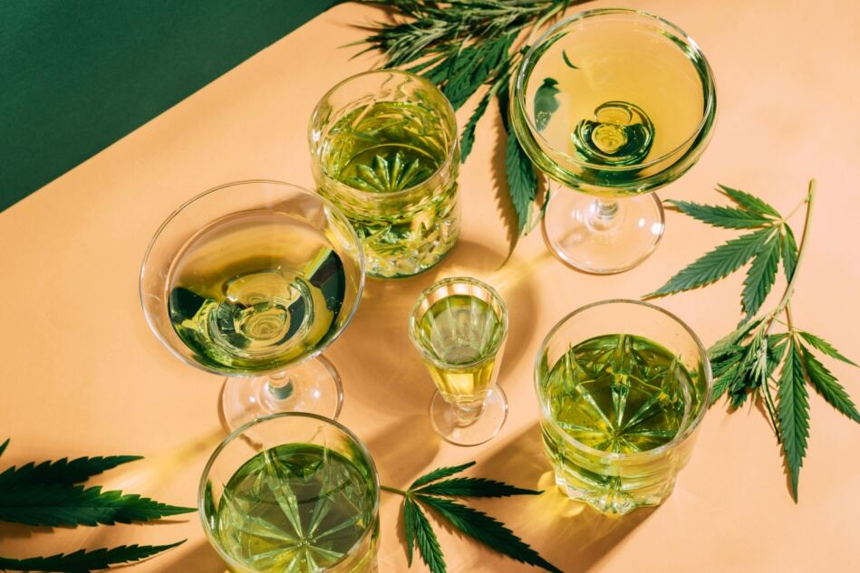 Hemp leaves and glasses sit on a table.
