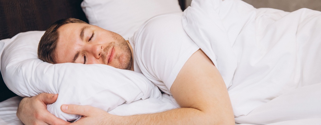 A man sleeps peacefully in bed.