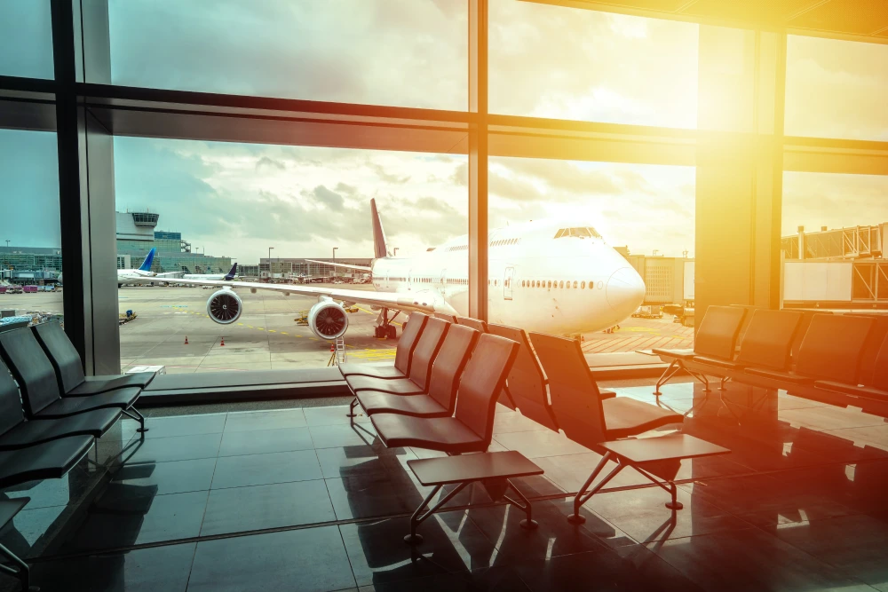 A commercial jet sits at the gate as seen from the waiting area inside the airport.