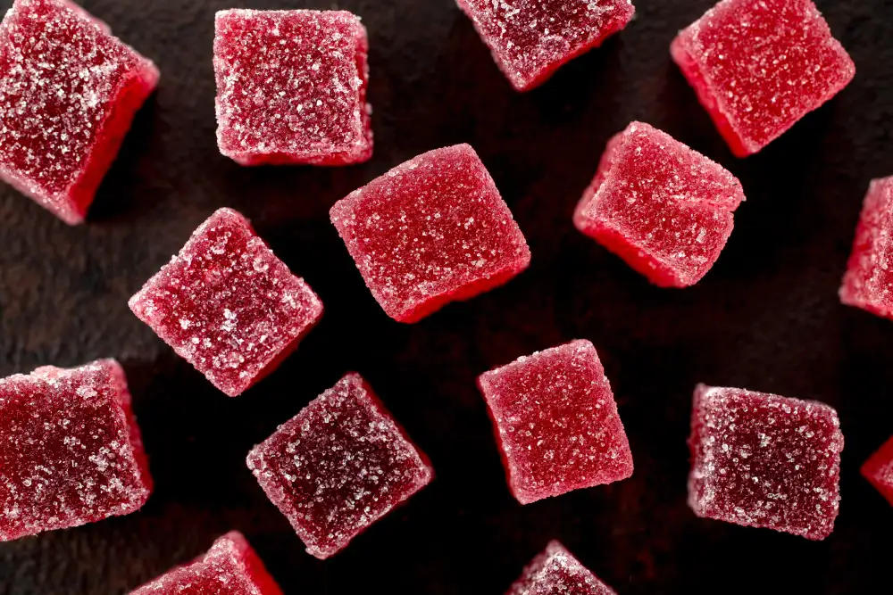 An overhead view of red THC gummies on a black background.