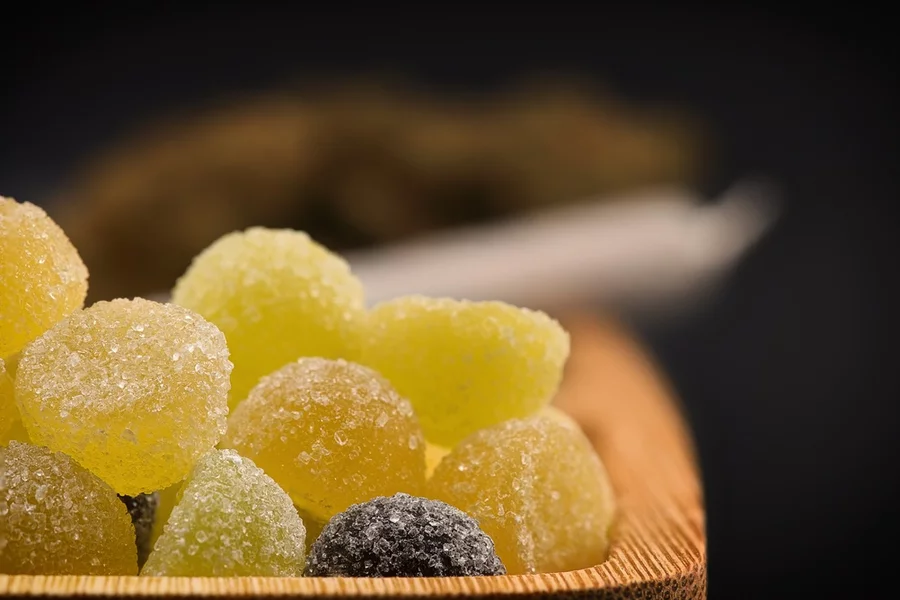 A small stack of gummies sits in a wooden dish.