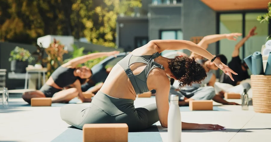 A yoga class practices outside on a sunny day.