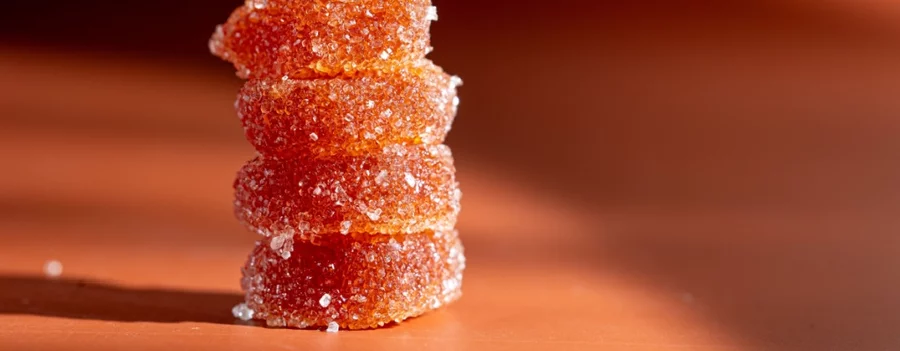 Four orange Delta 9 gummies sit in a stack in a close-up view.