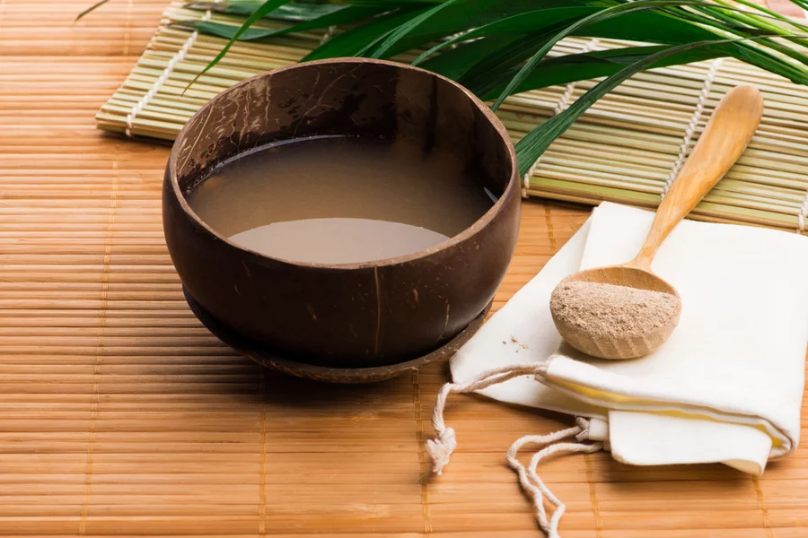 A traditional kava drink preparation, including liquid in bowl, powder, leaves, and more.