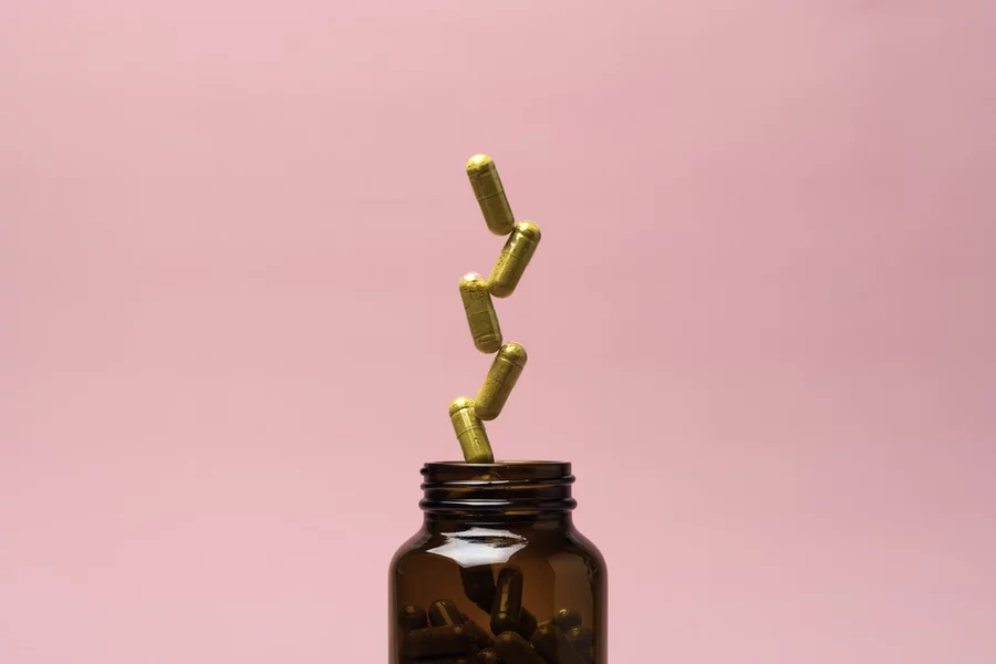 amber glass supplement bottle on pastel