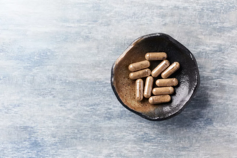 Ashwagandha capsules in a small bowl on a counter.