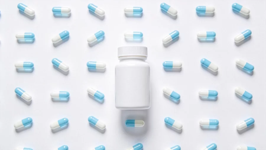 A white supplement bottle surrounded by a hypnotic pattern of blue and white capsules, with a “clean” aesthetic.