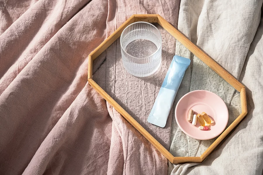 Dietary supplements seen from above on a glass tray, sitting on a bed.